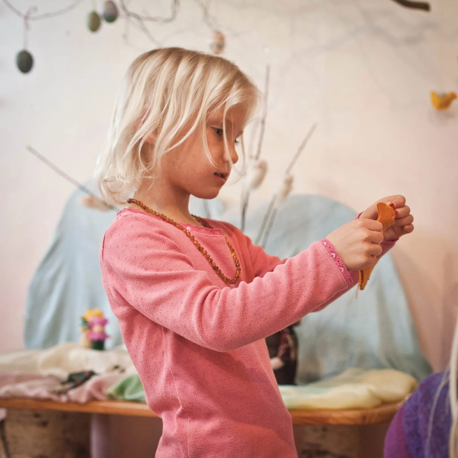 A kindergartener with a felted bird at the seasonal nature table.