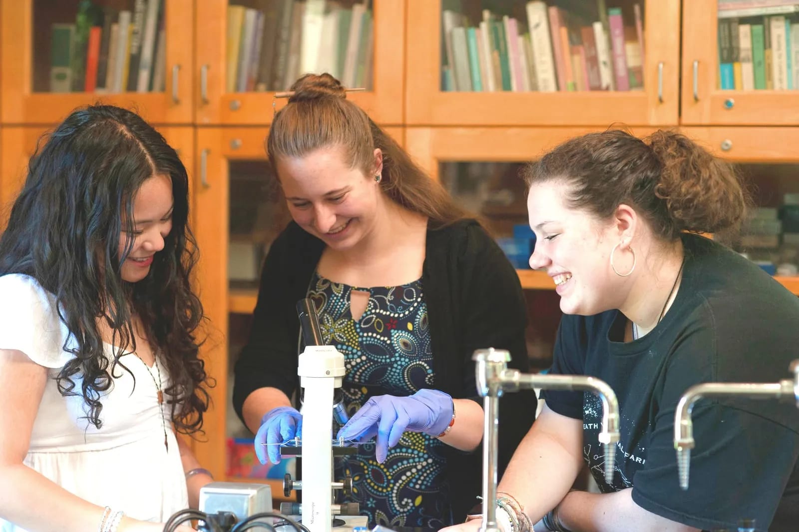 Three students share a microscope in the science lab.